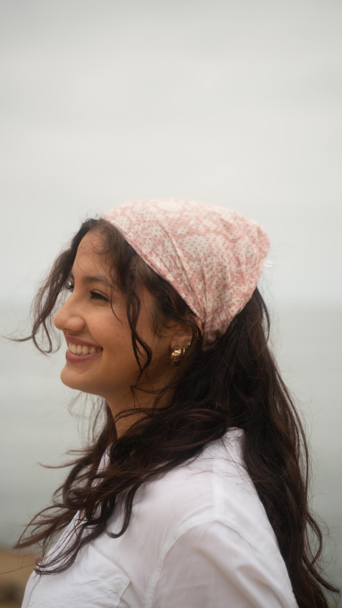Woman wearing a pink headscarf against a plain background