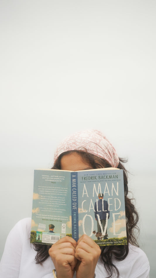 Person holding a book titled 'A Man Called Ove' against a plain background